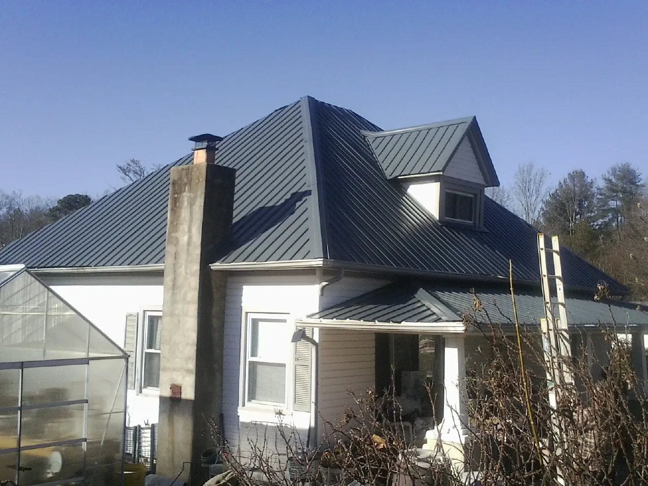 Dark blue standing seam metal roof on a white farmhouse with dormer — Slate & Tile Roof Repair by Roofing Brothers in East Longmeadow