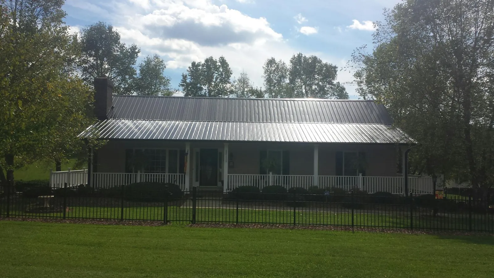 Gray metal roof on a brick ranch with a full width front porch — Gutter Guard Installation work by our crew in East Longmeadow