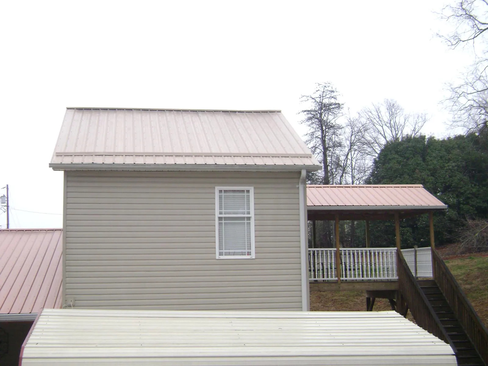 Tan metal roofs on a two story addition and attached porch, from a Roof Replacement job in East Longmeadow