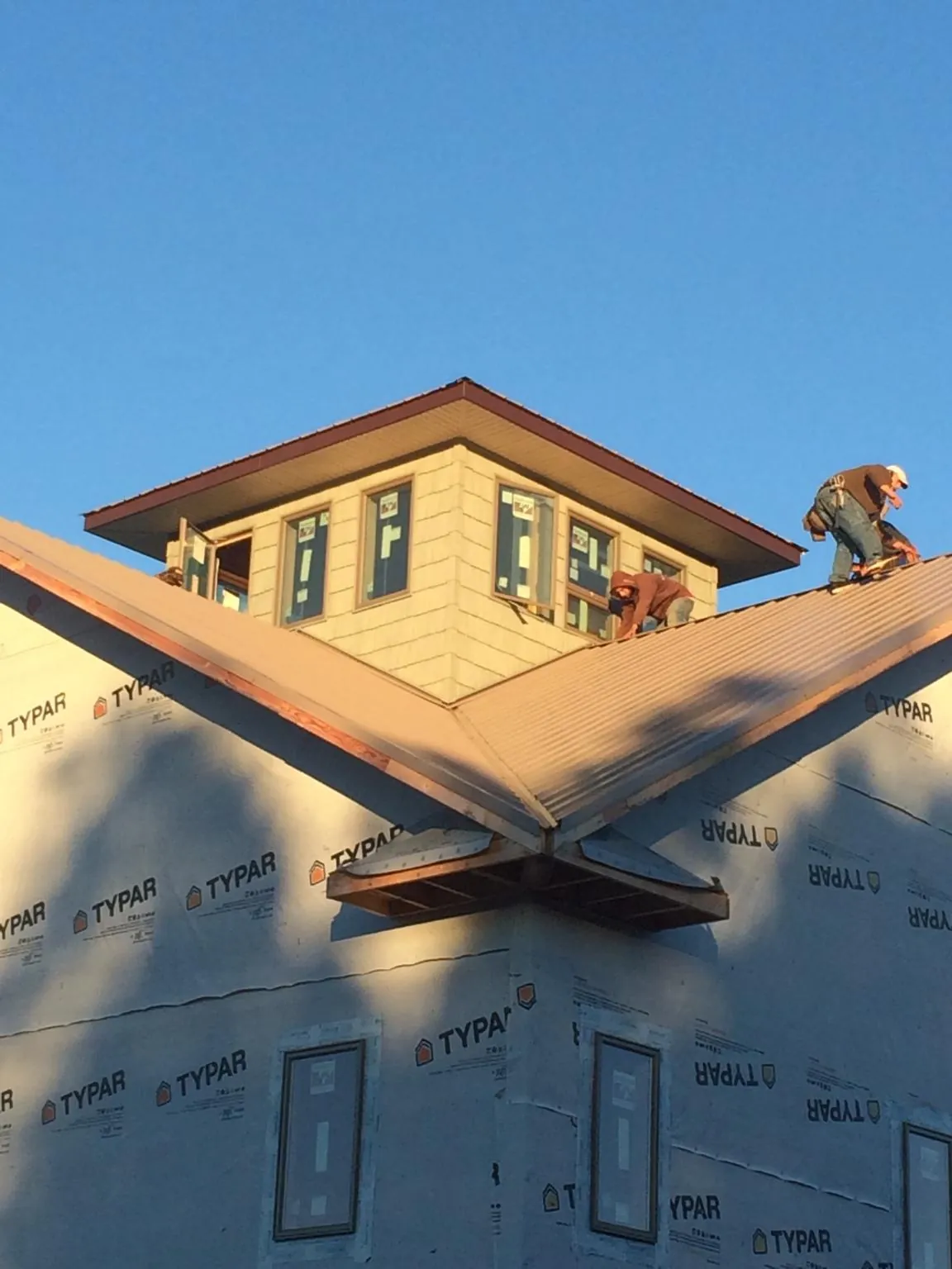 Roofers working around a rooftop cupola on a new metal roof at sunset — Roof Waterproofing in East Longmeadow by Roofing Brothers
